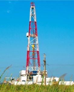 Red and White hydraulic fracturing tower with grass in the foreground